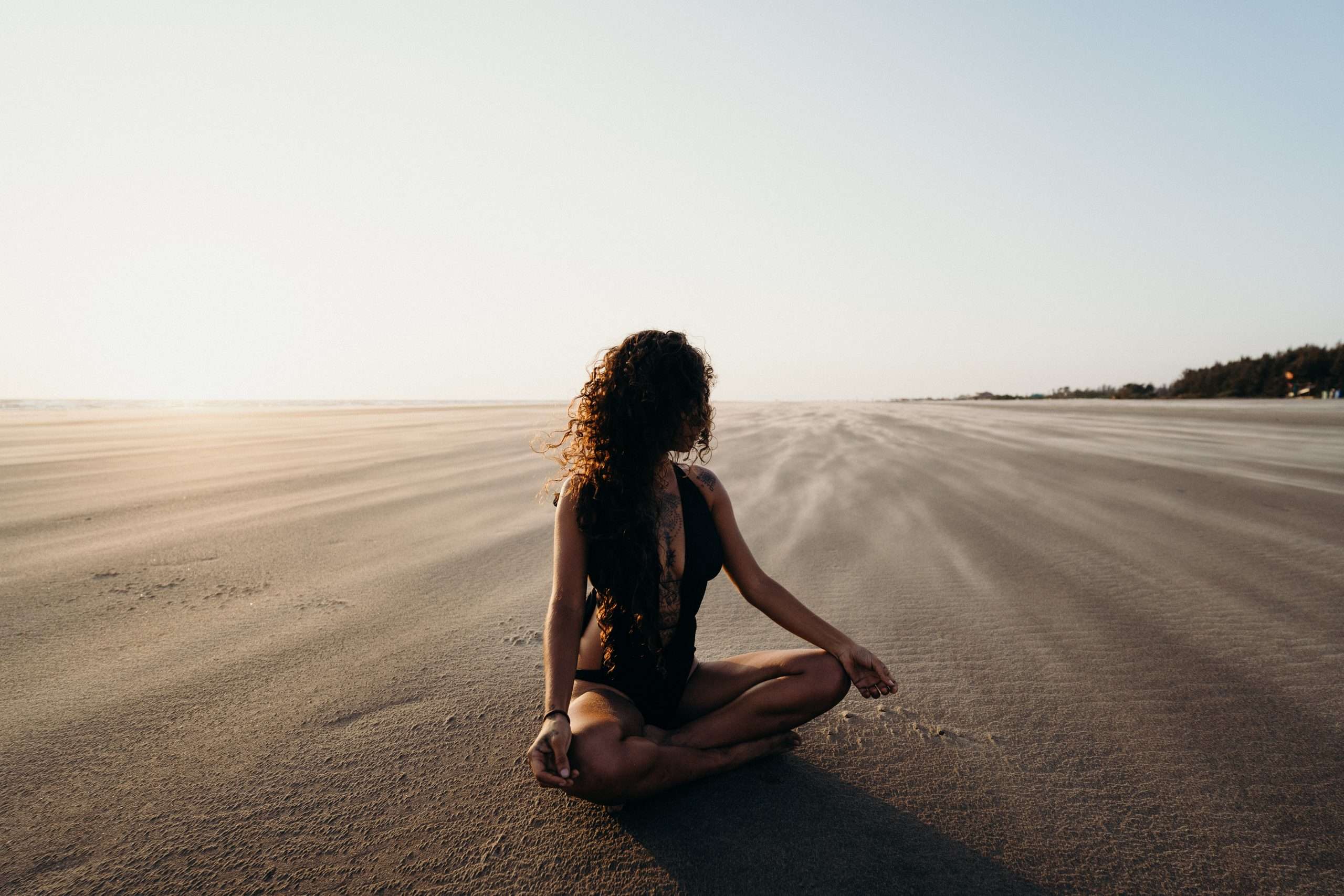 woman-sitting-on-sand-meditating