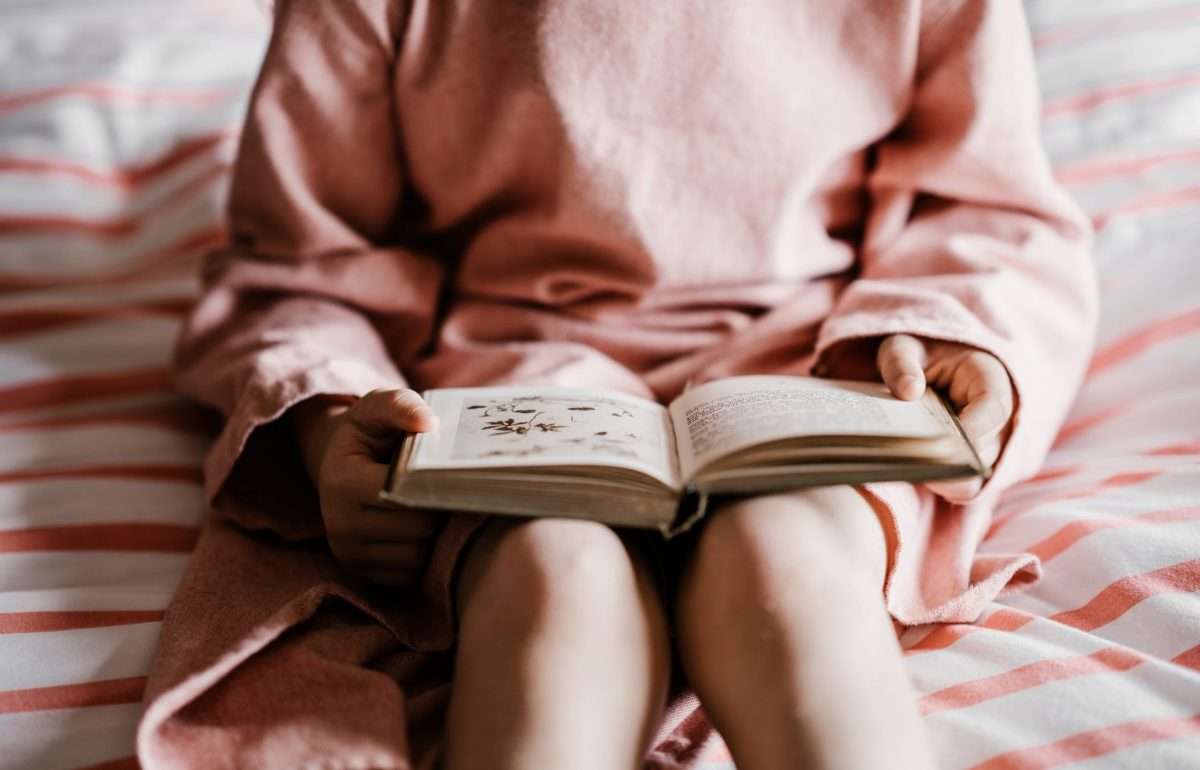 child-holding-open-book-in-lap