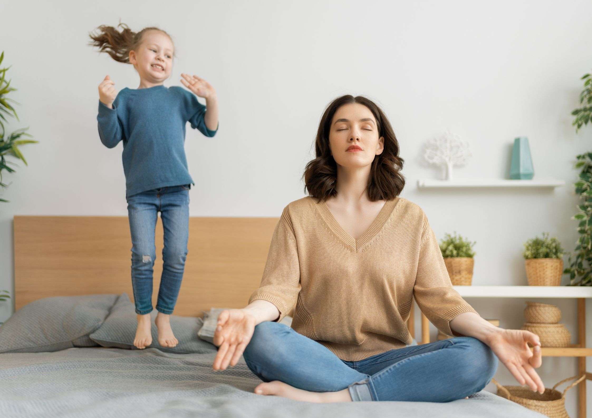 mum-sitting-in-meditation-pose-on-bed-daughter-jumping-on-bed-defining-boundaries-as-a-mum-blog-post