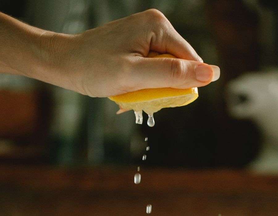 side-view-hand-squeezing-lemon-dark-background