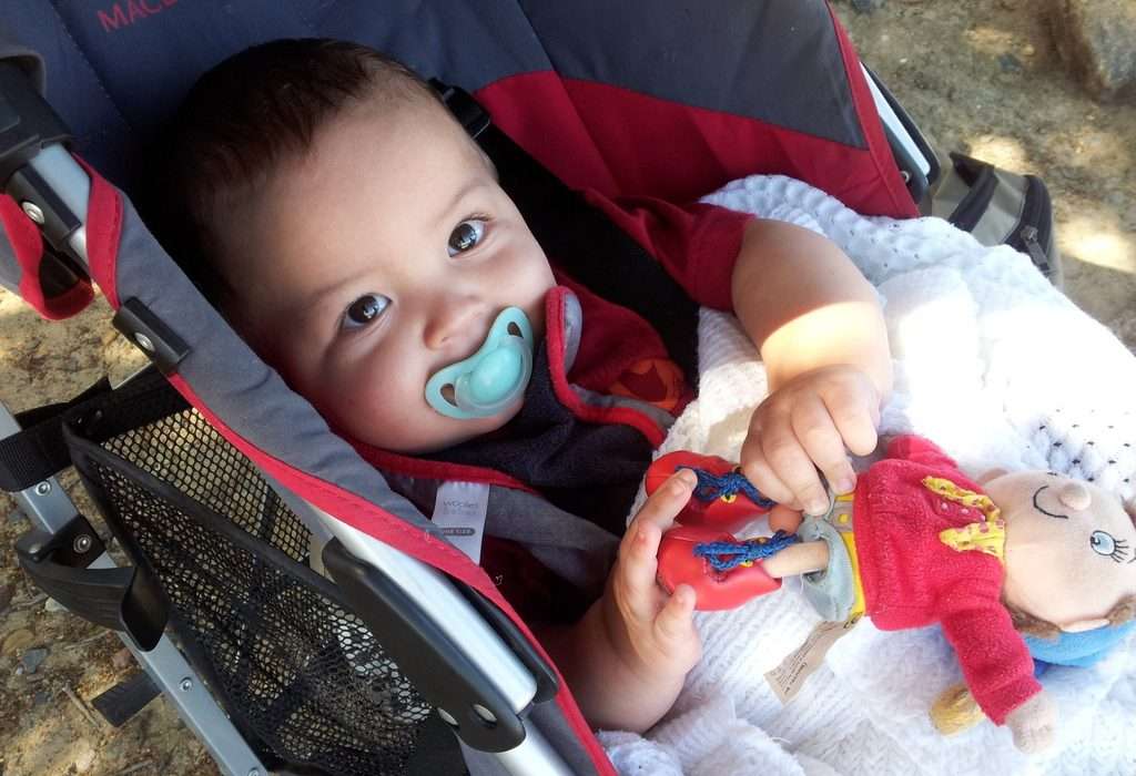 baby-in-stroller-dummy-in-mouth-big-brown-eyes