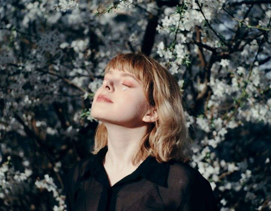 woman-in-front-of-cherry-blossom-tree-shoulder-length-hair-eyes-closed-head-lifted-to-the-sun-contented-expression-mindfulness-blog-post
