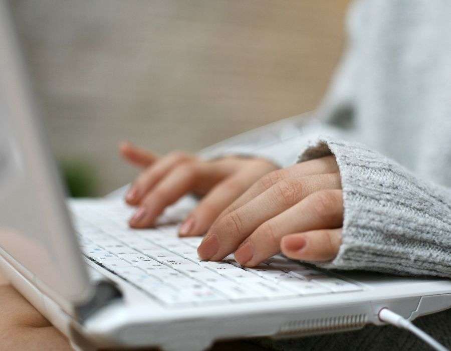 close-up-hands-typing-on-laptop-wooly-grey-jersey-covering-part-of-hands