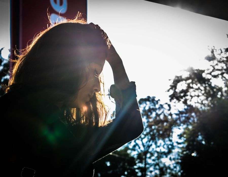 woman-backlit-hand-on-head-sad-expression-self-forgiveness-blog-post