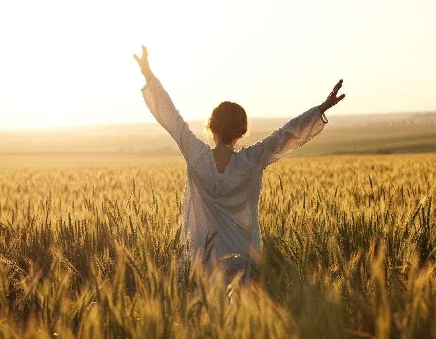 woman-in-field-sunset-wearing-white-arms-outstretched-to-the-sky-know-your-worth-blog-post
