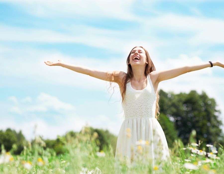 smiling-woman-in-field-arms-out-sense-of-self-worth