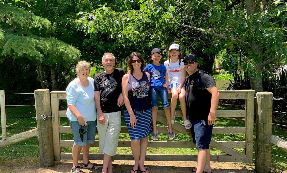 family-portrait-standing-in-front-of-large-farm-fence-trees-in-background-guidelines-from-parents-blog
