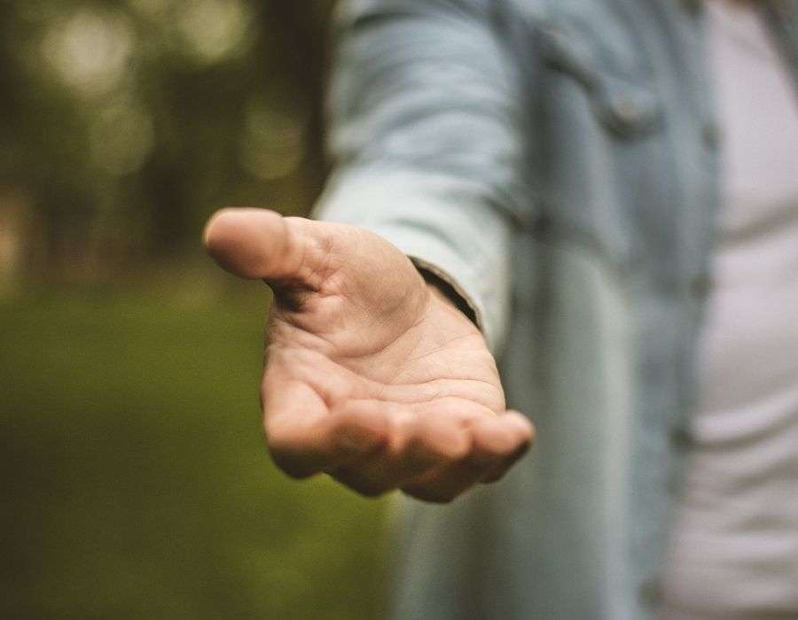 hand-reaching-out-to-help-blurred-forest-background
