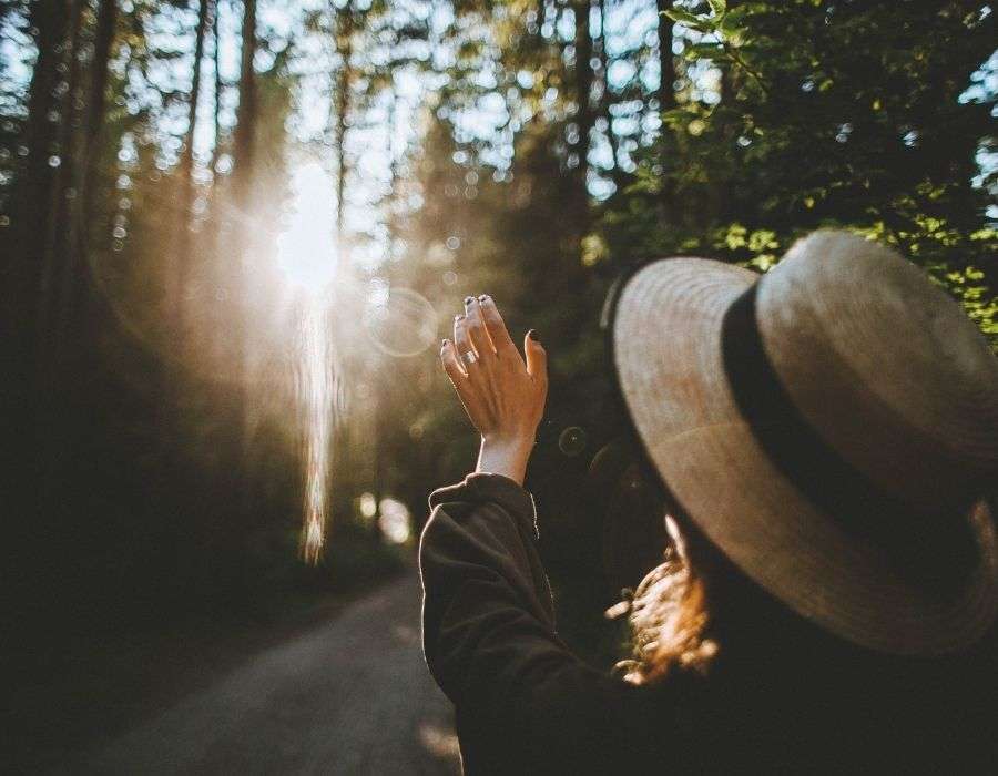 woman-sun-through-trees-hat-on