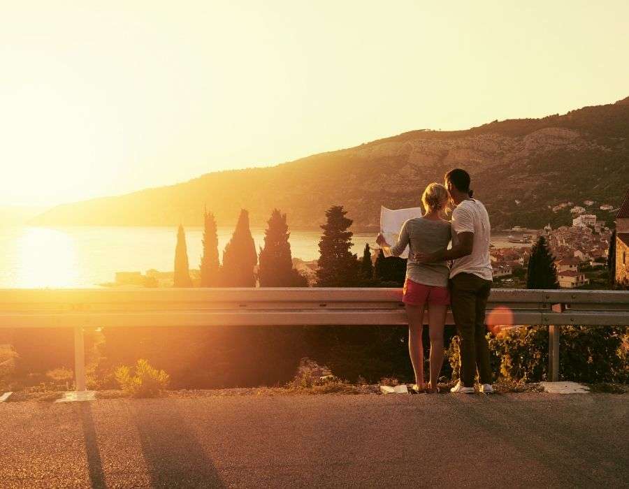 couple-standing-arms-around-each-other-from-behind-looking-at-sunset-chasing-your-dreams-blog-post