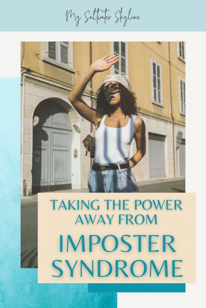 woman-dark-curly-hair-jeans-white-tank-top-standing-on-historic-street-hand-covering-sun-on-face-words-overlayed-taking-the-power-away-from-imposter-syndrome