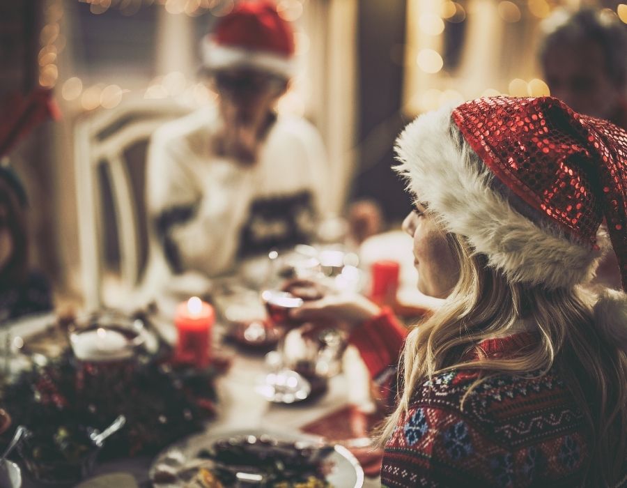 sitting-at-the-christmas-table-wearing-santa-hats-celebrating-what-to-focus-on-during-the-holiday-season-blog-post