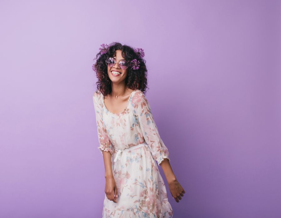 woman-white-dress-flower-pattern-long-hair-smiling-against-purple-wall-background-embrace-change-blog