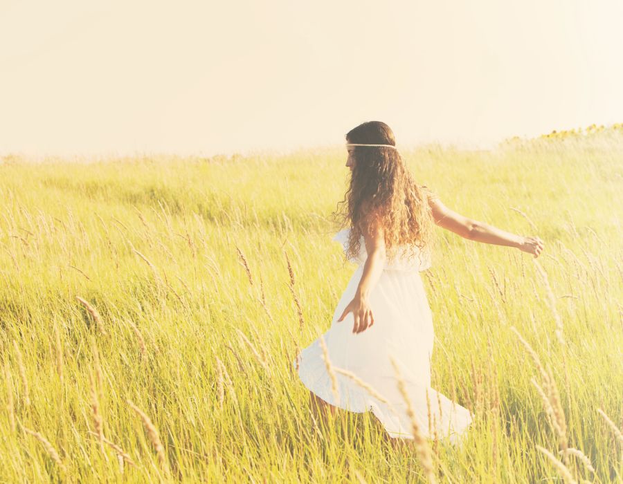 free-spirit-woman-white-dress-walking-through-field
