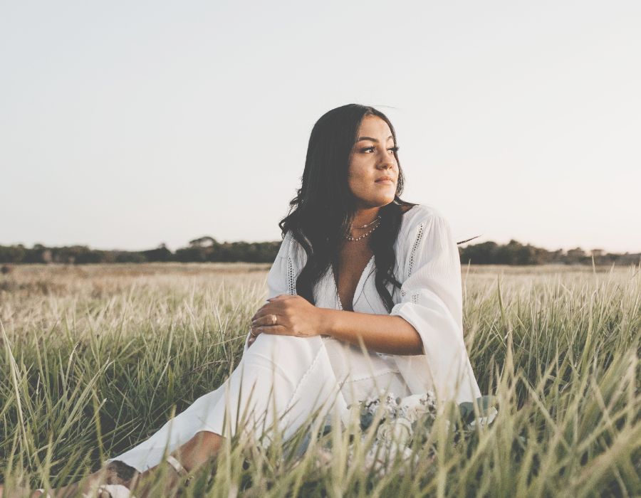woman-dark-hair-sitting-in-field-at-dusk-self-awareness