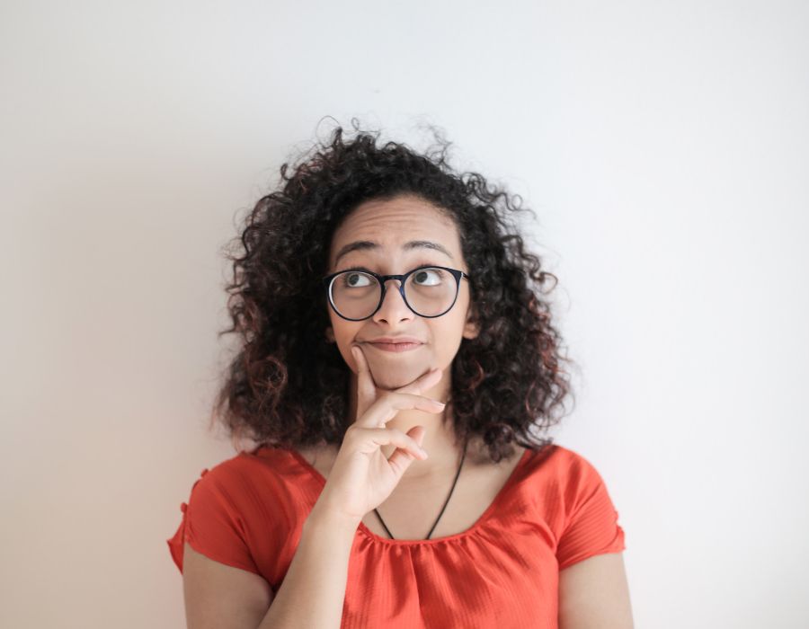 why-positivity-matters-blog-post-woman-looking-confused-curly-dark-hair-orange-shirt