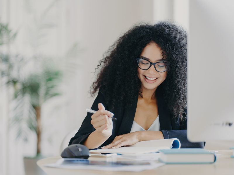 woman-at-desk-writing-happy-face-inspired-action-blog-post