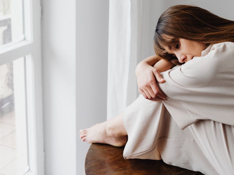 how-to-be-happy-again-blog-post-woman-dark-hair-curled-up-sad