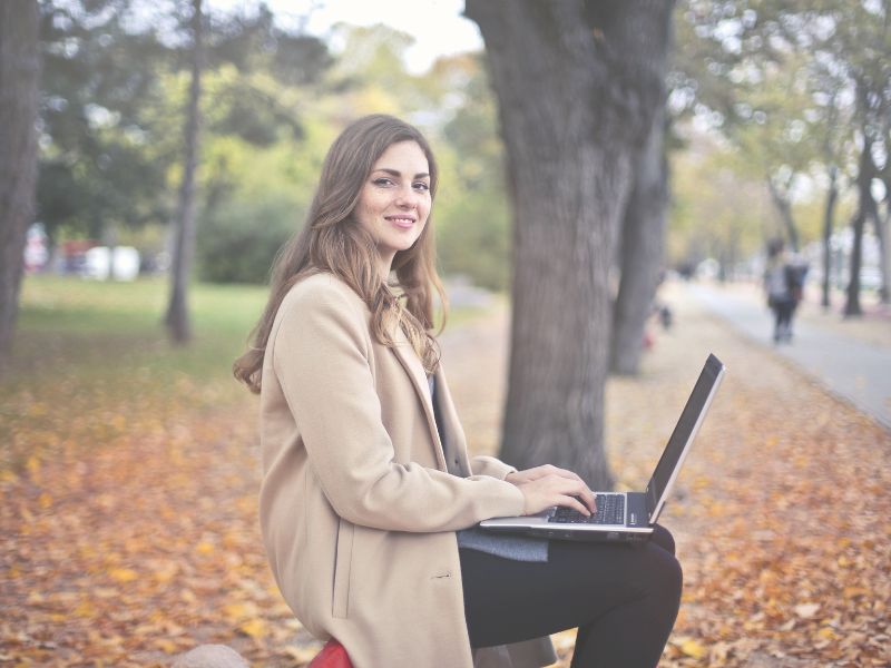 woman-smiling-on-park-bench-with-laptop-believe-in-yourself-blog-post